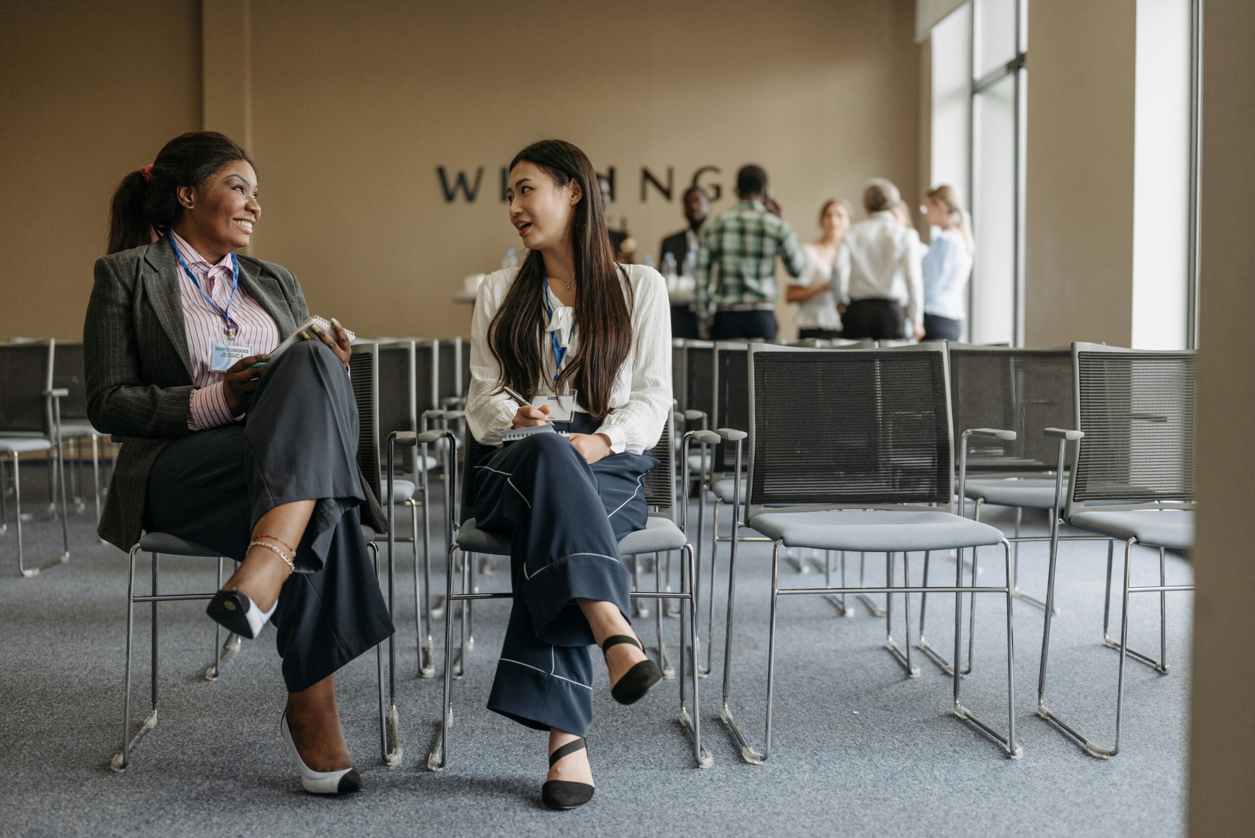 Two women sitting and talking in a conference room.